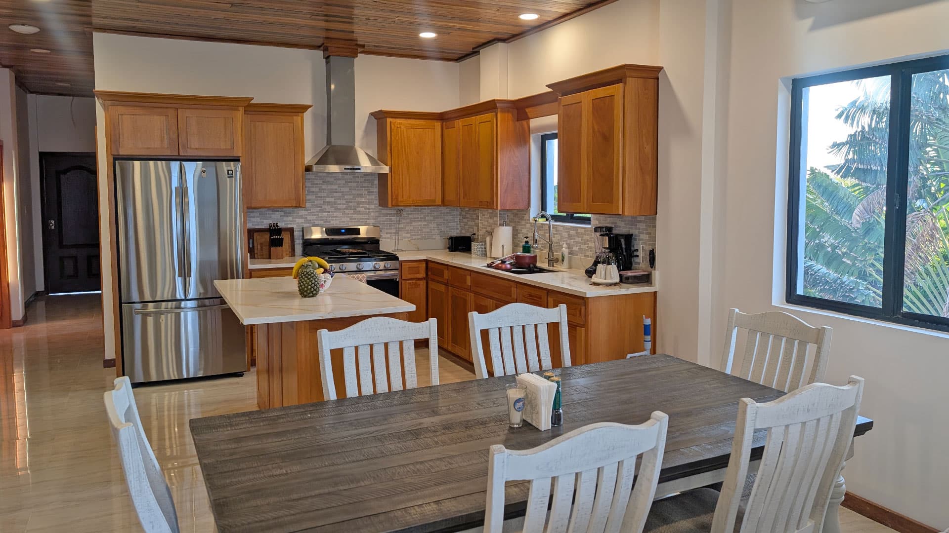 Modern kitchen with wooden cabinets, stainless steel appliances, and a dining table.
